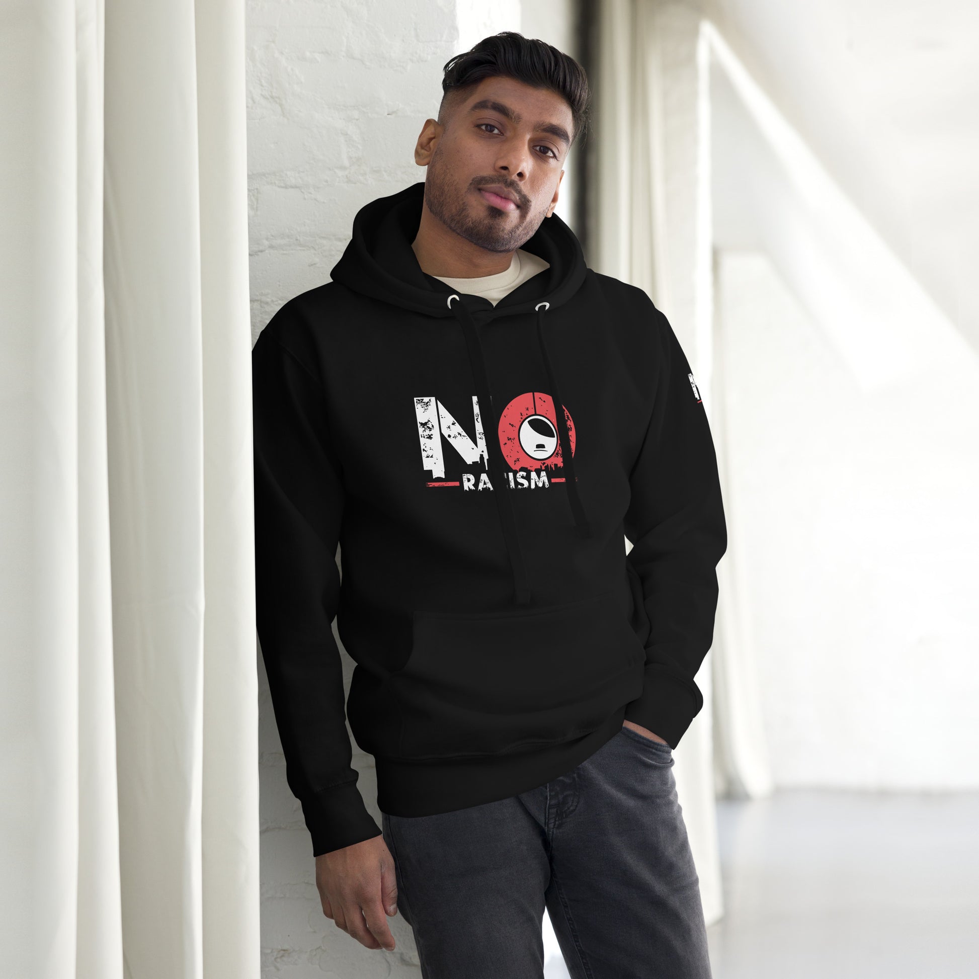 Model trägt NO RACISM Unisex Hoodie im Streetwear‑Look mit Jeans.