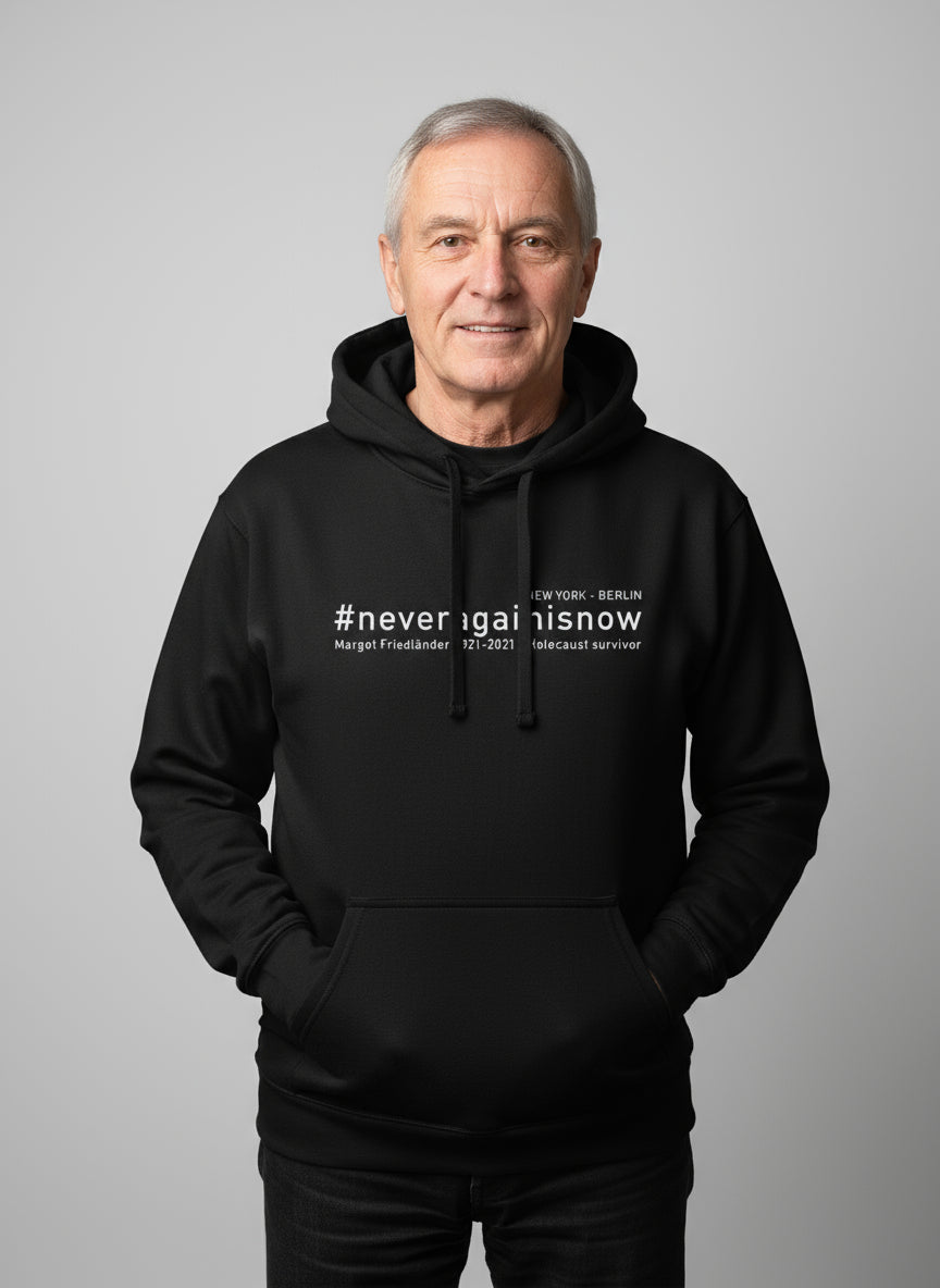 Ältere Person steht frontal, trägt schwarzen Hoodie mit #neveragainisnow und Margot Friedländer Nennung.
