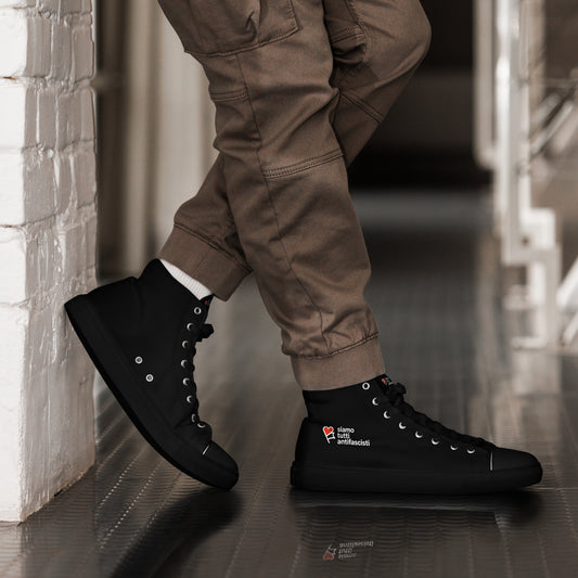 „Schwarze High‑Top‑Sneaker mit weißer Sohle und weißen Schnürsenkeln. Auf der Außenseite befindet sich ein rotes Herz mit dem italienischen Schriftzug ‚siamo tutti antifascisti‘ als politisches Statement.“