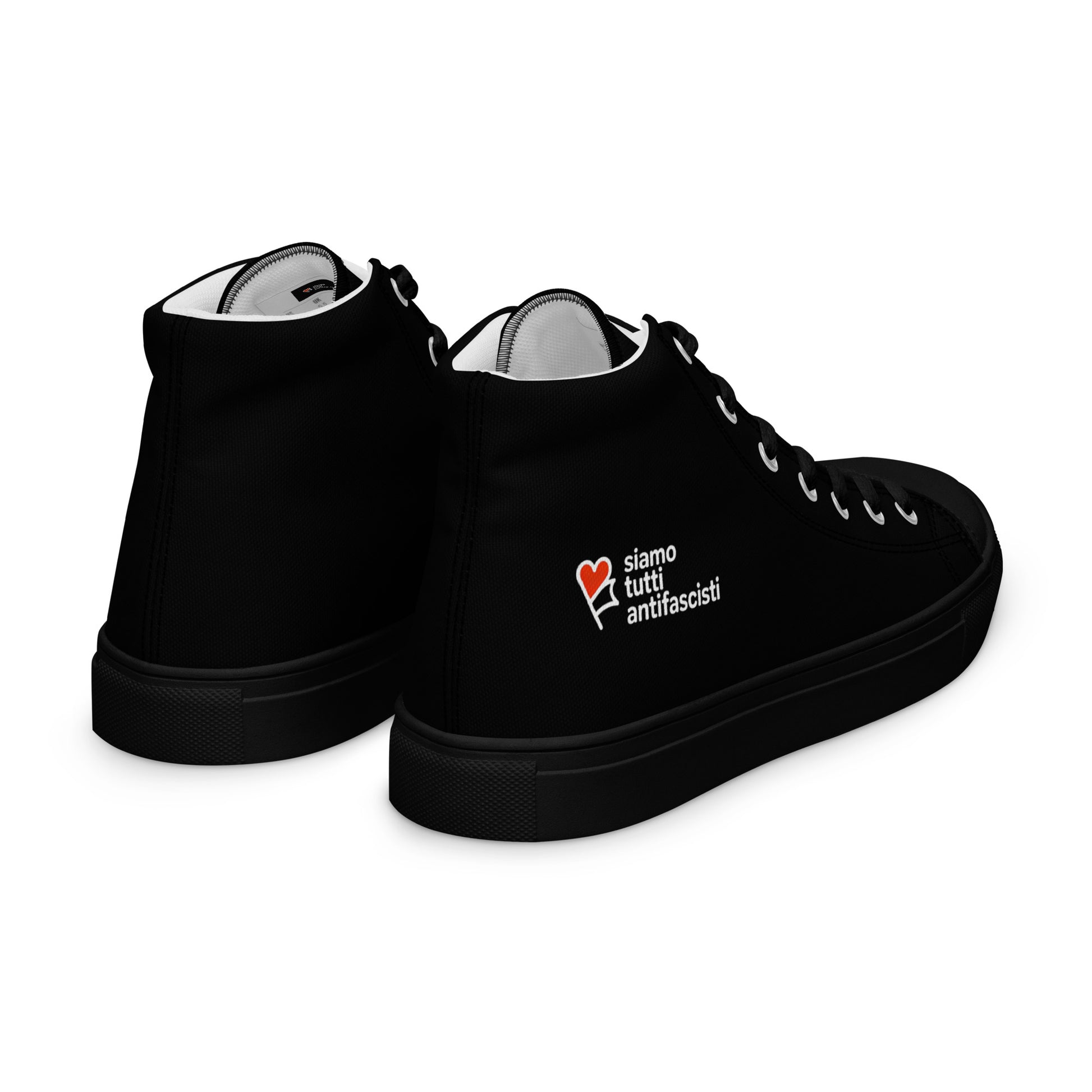 „Canvas‑Schuhe in Schwarz mit gepolstertem Kragen. Seitlich ist ein rotes Herz mit dem Schriftzug ‚siamo tutti antifascisti‘ aufgedruckt, das Solidarität und Antifaschismus ausdrückt.“

